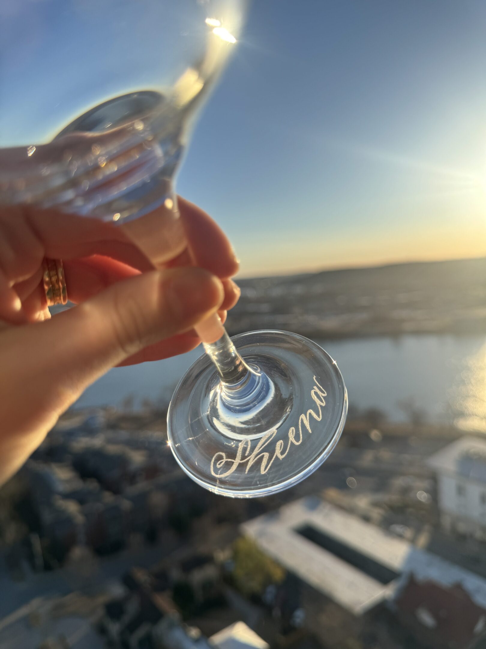 Hand holding wine glass with sunset view
