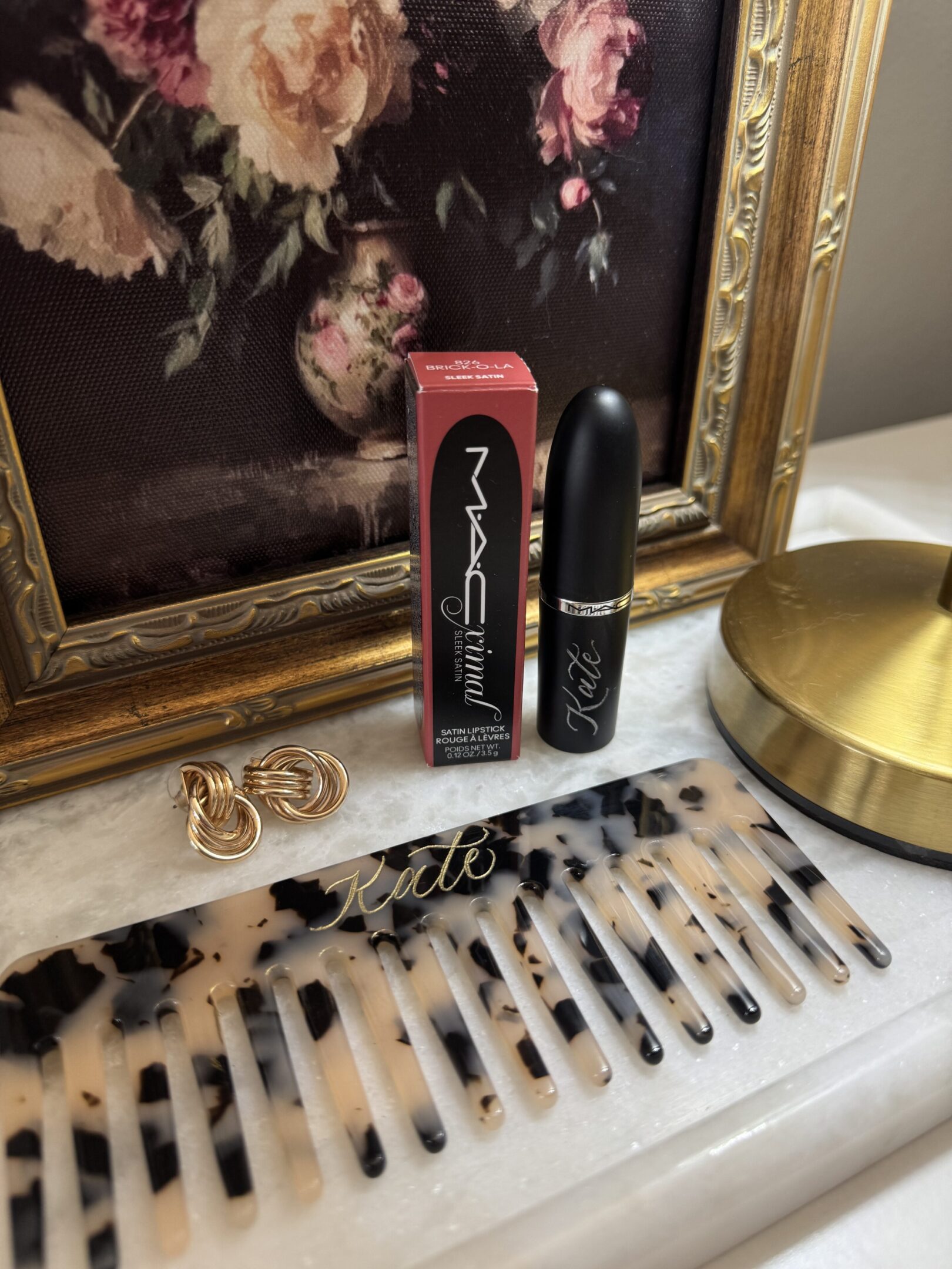 MAC lipstick and jewelry displayed on a marble surface with elegant decor.