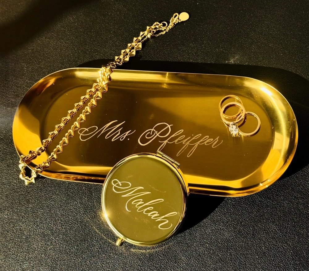 Gold tray with engraved jewelry and a ring.