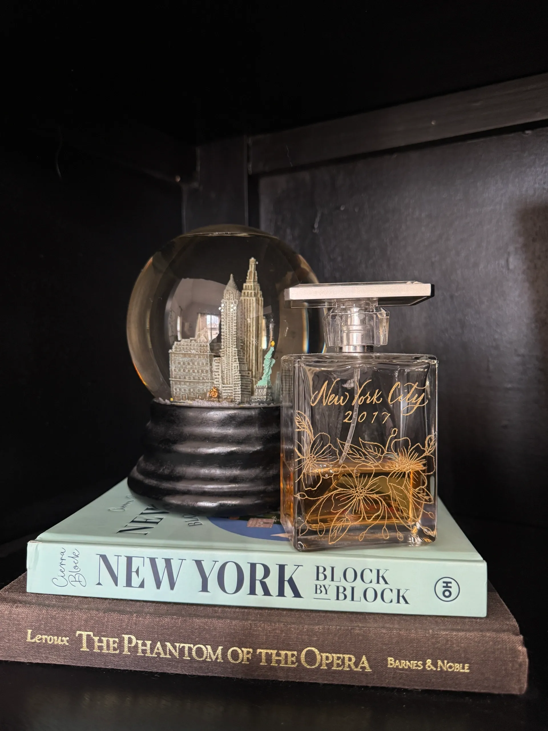 Decorative perfume bottle and globe on stacked books.
