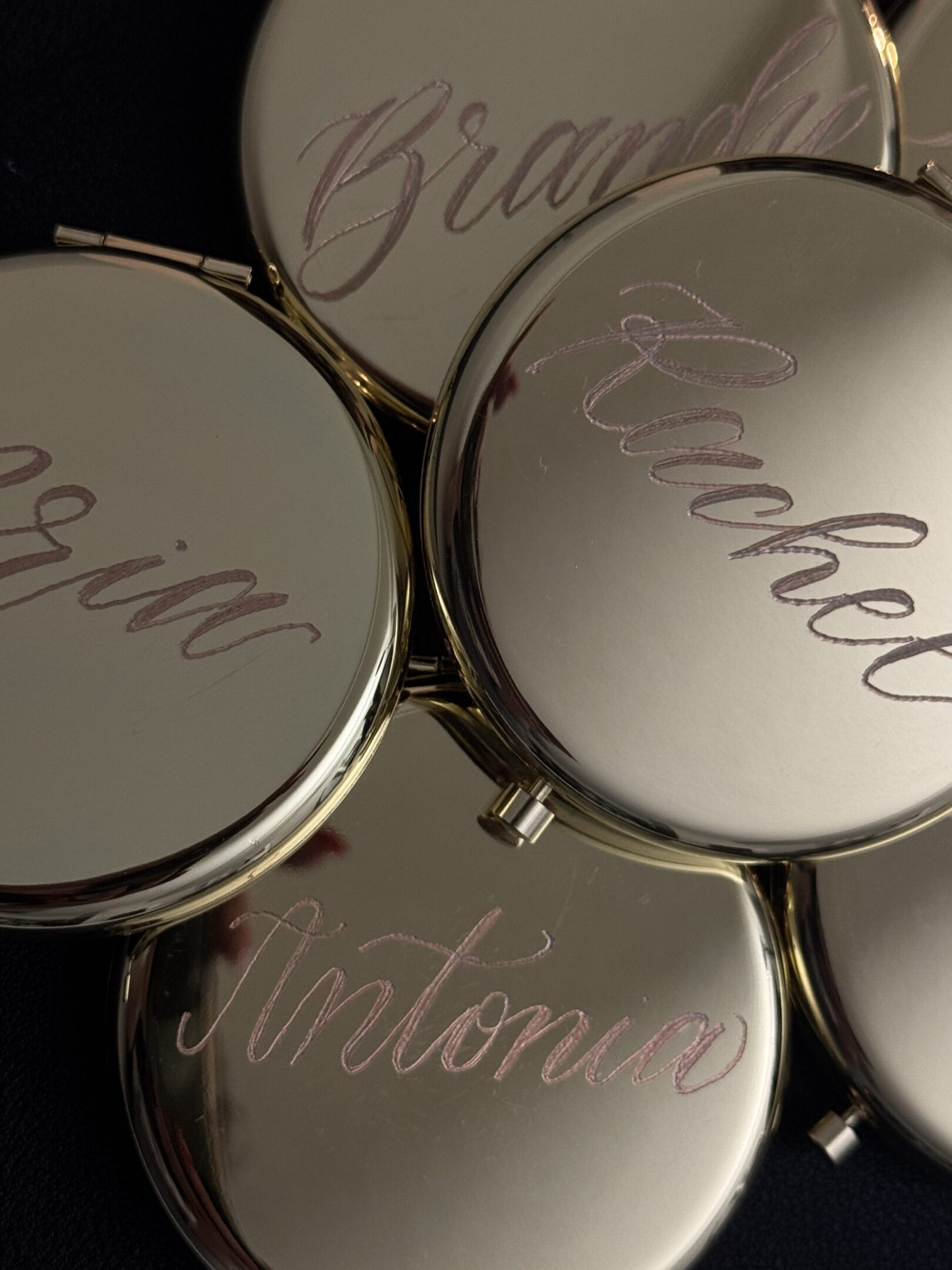 Close-up of engraved silver or metal items with cursive names.