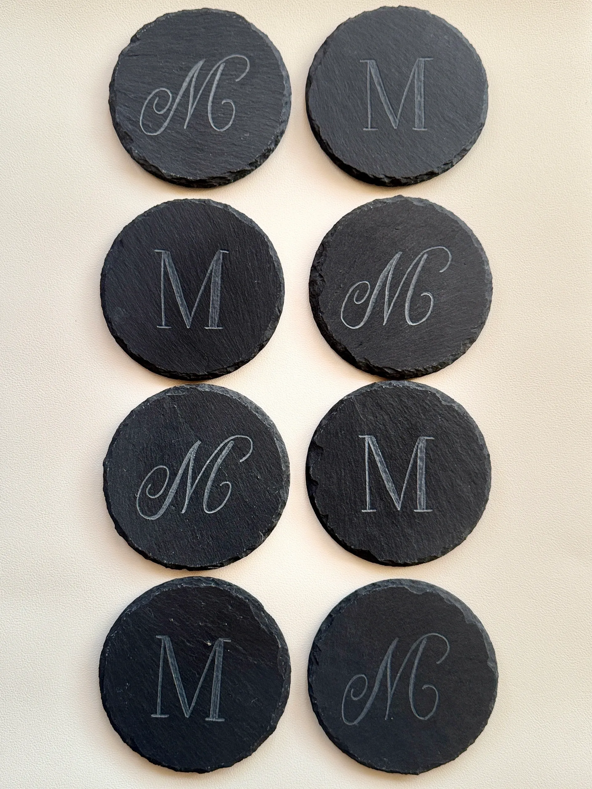 Black round tokens with white initials M and MC in elegant fonts.