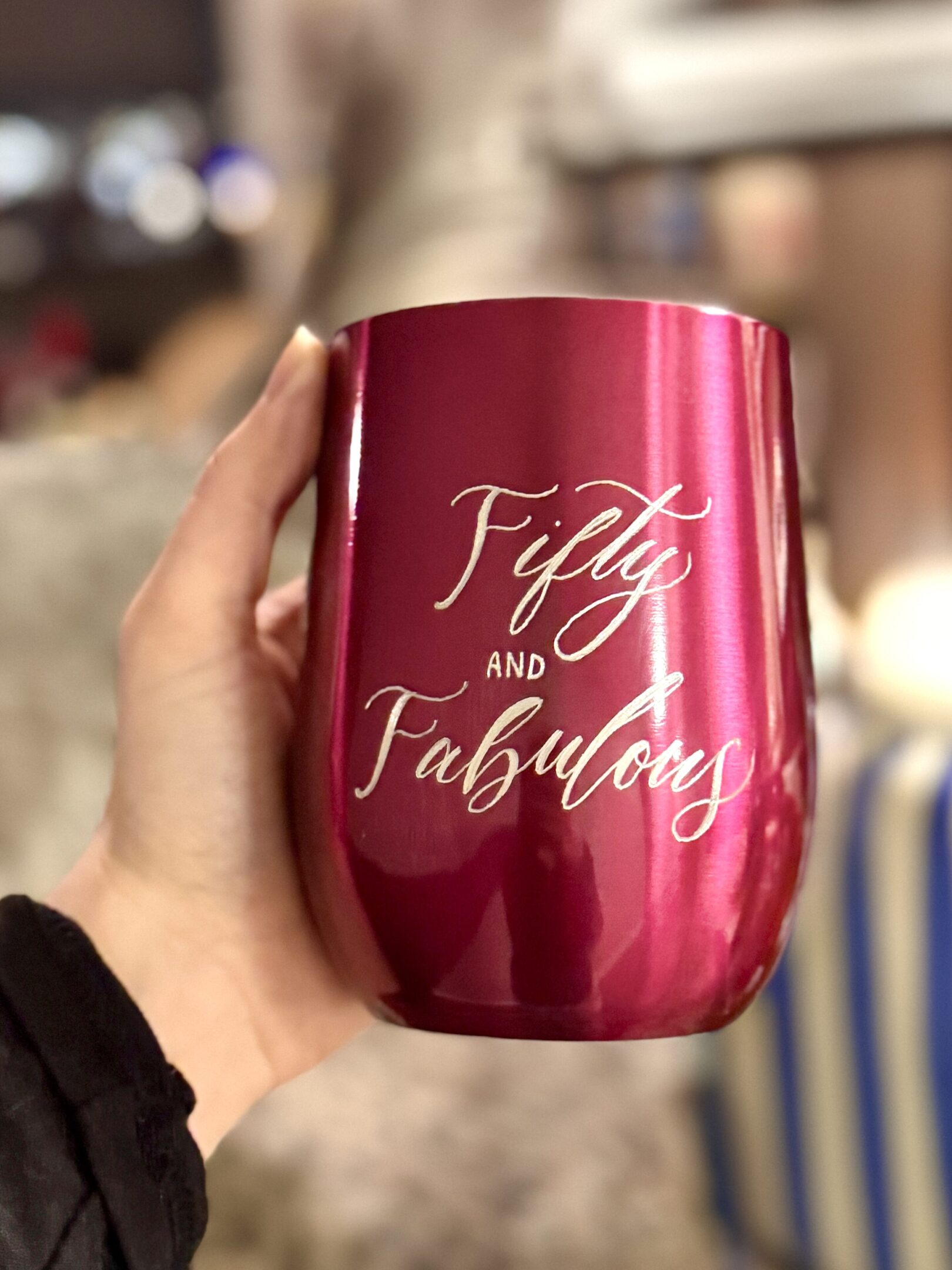 A red metallic tumbler with 'Fifty and Fabulous' inscription.