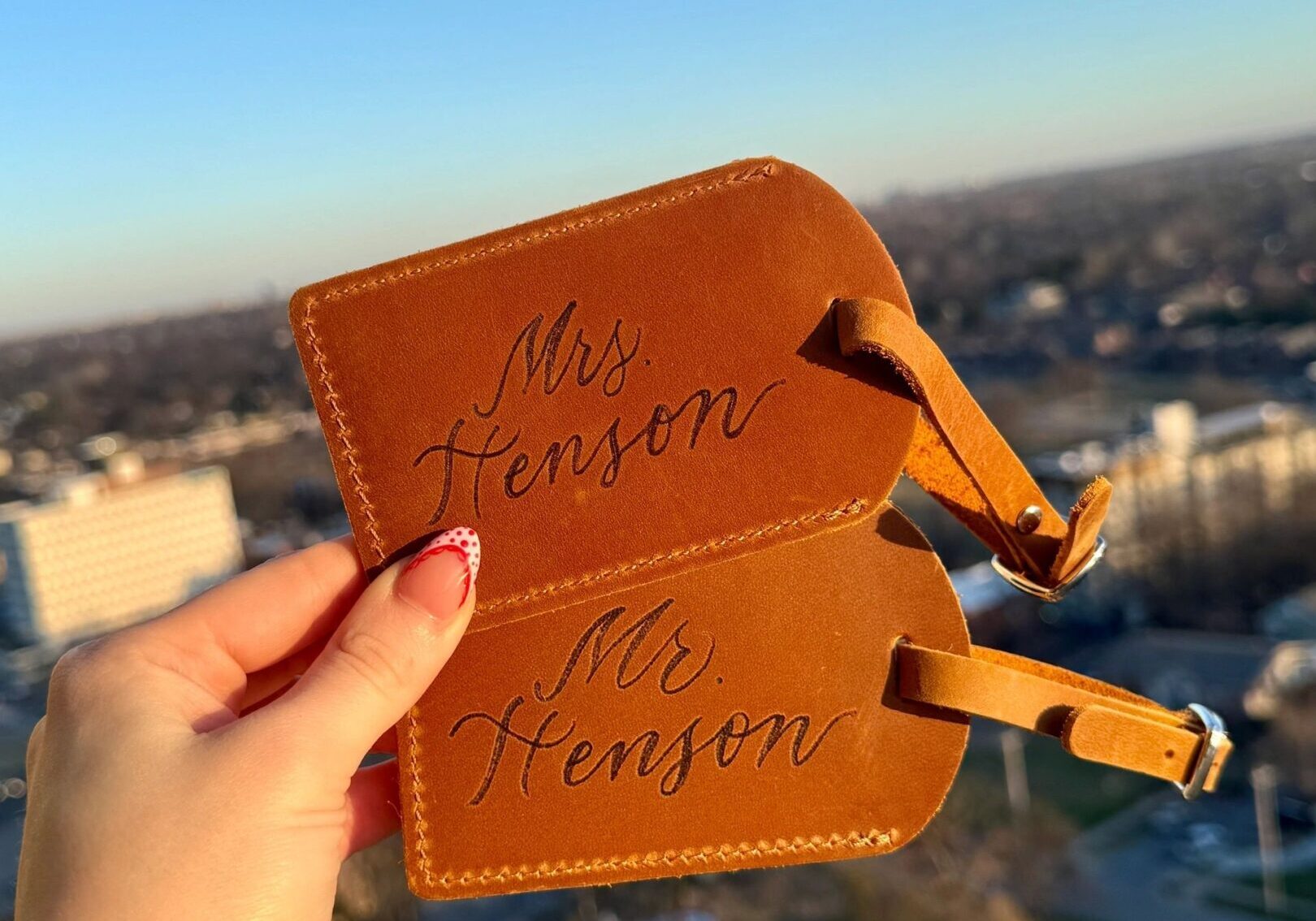 Two leather luggage tags held against a city backdrop.